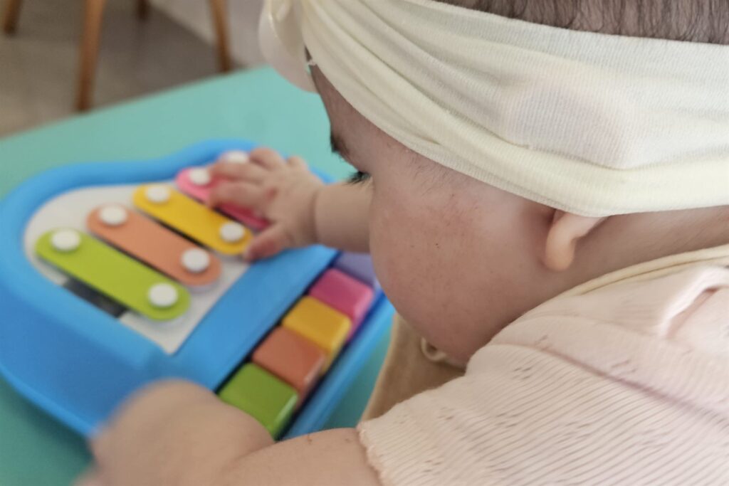 Bebê brincando com xilôfone durante estímulo do desenvolvimento infantil