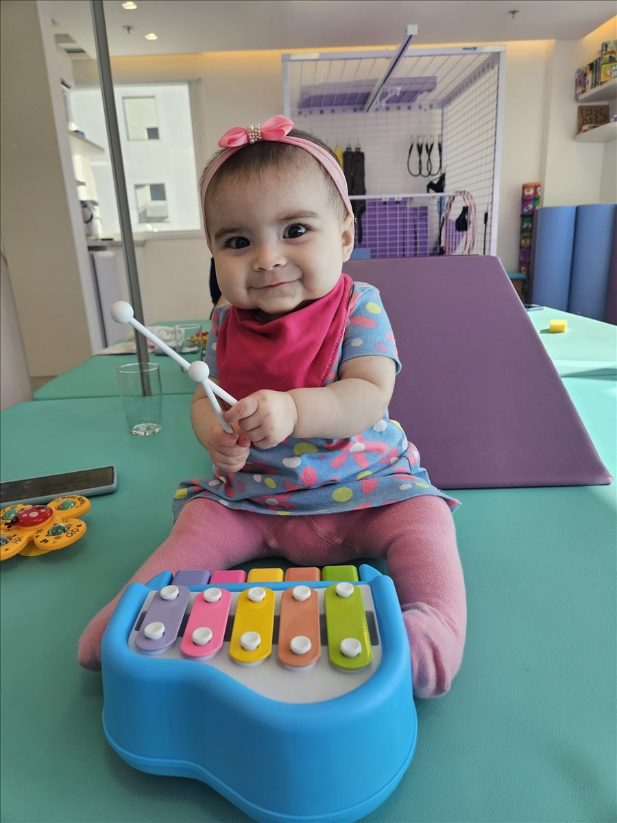 Bebê brincando com xilofone durante estimulação da coordenação motora fina na Clínica AmarElo