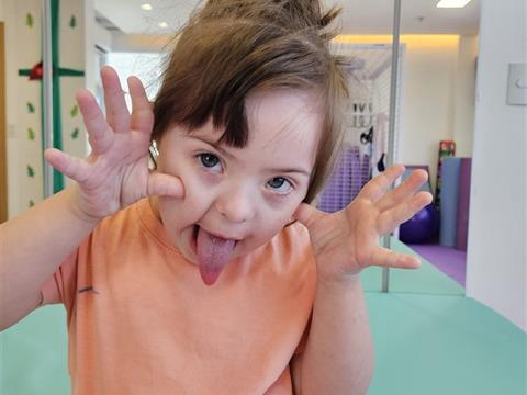 Criança com síndrome de Down sorrindo em atividade terapêutica na Clínica AmarElo