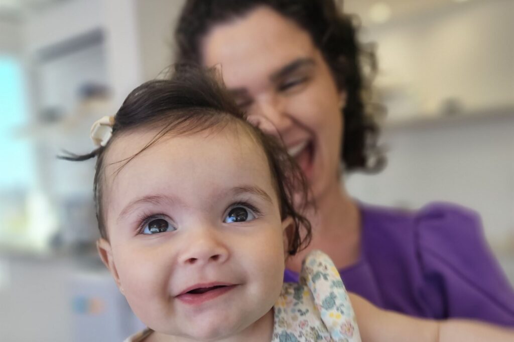 Fisioterapeuta sorrindo com um bebê no colo durante atendimento de fisioterapia infantil em Porto Alegre